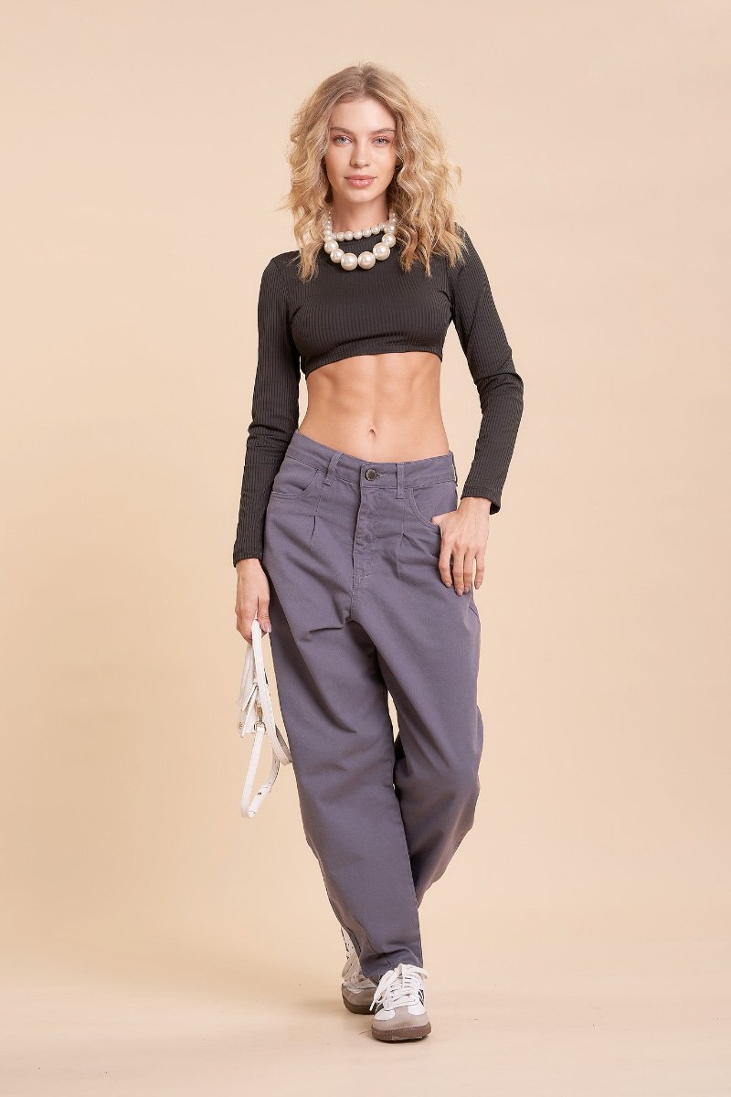Modelo de corpo inteiro com a calça Cassia chumbo slouchy, cropped preto de manga longa e tênis branco