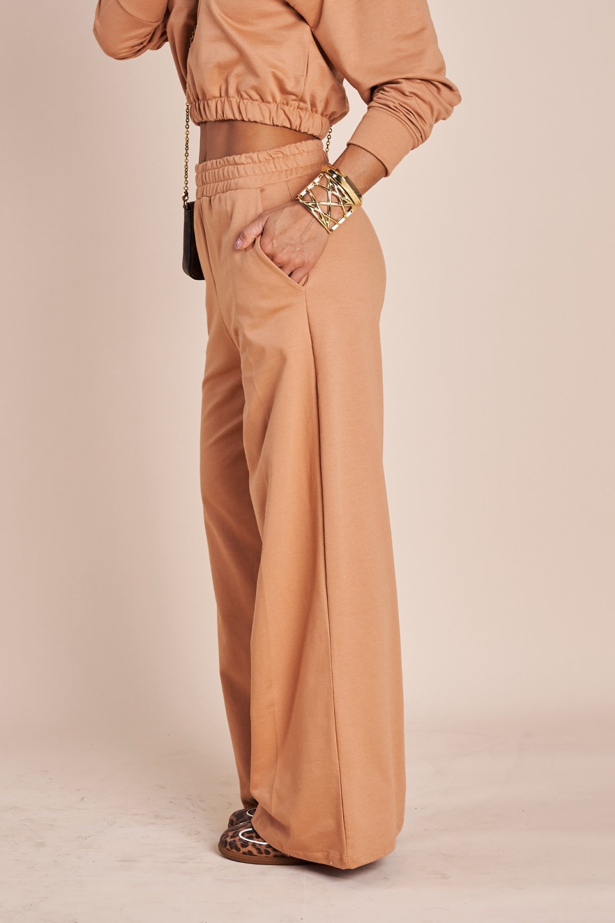 Detalhe da calça wide leg de moletinho terracota, da cintura franzida até a barra que toca o chão, com bolso lateral embutido