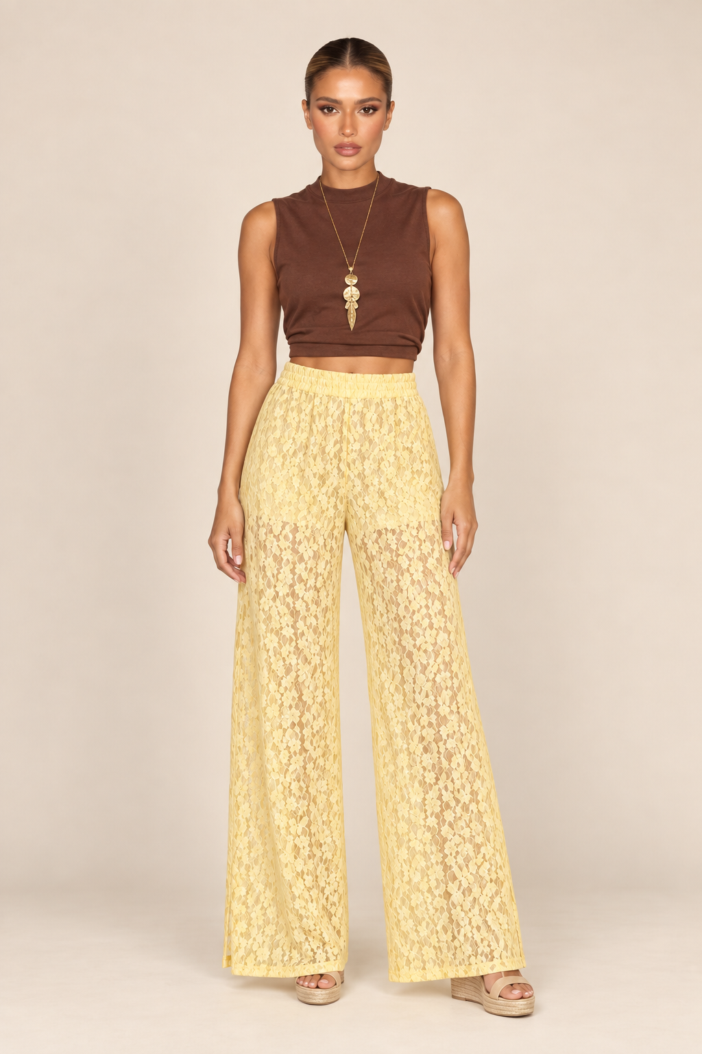 Calça pantalona de renda amarelo manteiga fotografada sozinha, mostrando a trama floral vazada