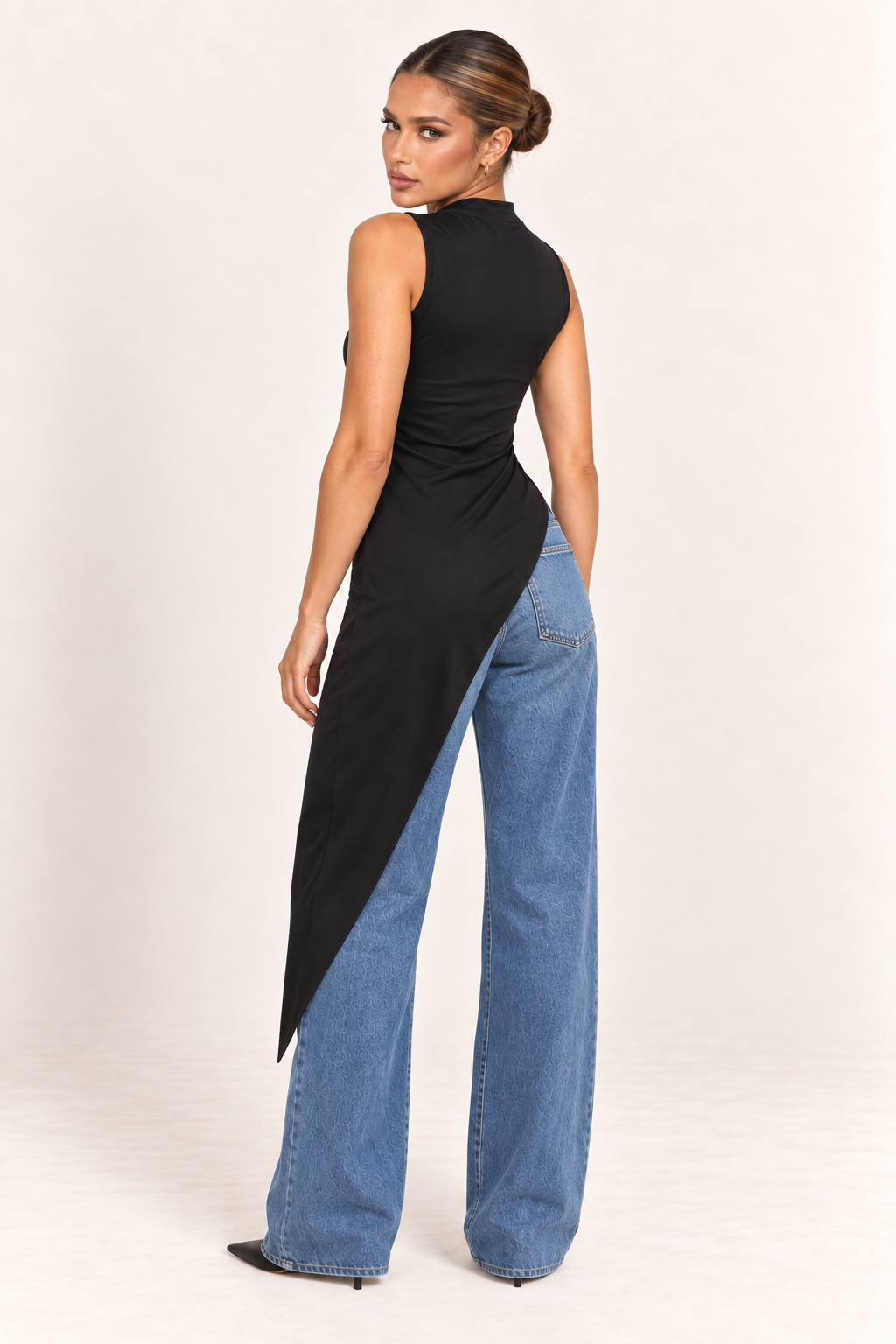 Modelo veste a blusa preta de gola alta com a ponta caindo sobre calça jeans clara de perna larga